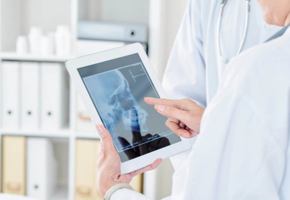 Close-up image of female doctor examining scull x-ray on screen of digital tablet